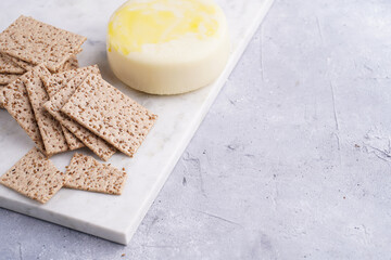 Healthy crunchy crisp crackers with sesame seeds and round cheese kashkaval on marble board