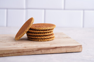 Stroopwafel - traditional dutch sirup waffles with caramel filling - stacked on top of each other on a wooden board, white kitchen