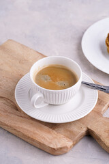 Stroopwafel - traditional dutch sirup waffles with caramel filling - stacked on top of each other on a wooden board, white kitchen and a cup of coffee in white porcelain cup