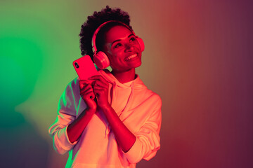 Portrait of beautiful trendy cheerful girl listening hit pop single pastime isolated over bright...