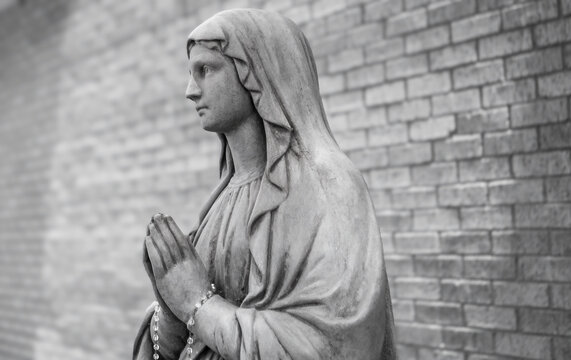 Cement statue of Mother Mary with a rosary