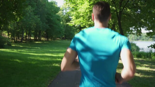 Rear view shot oy man running in public park during summer