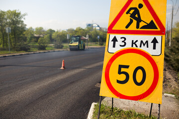 Road works sign on the road. Repair work of road signs and a bypass arrow
