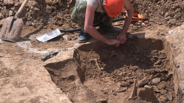 Young archeologist works on an archaeological site at morning sun rays at summer heat