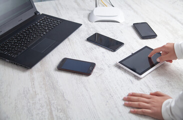 Girl using tablet. Internet router with smartphones and laptop computer on the desk. Network, Technology