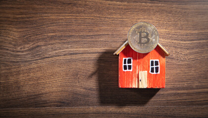 Obraz na płótnie Canvas Bitcoin and house model on the wooden table.