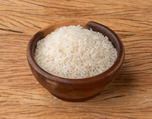 Raw white rice in a bowl over wooden table