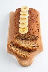On a white background, banana bread with banana slices on a wooden board.