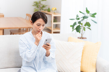 ソファーに座るミドル女性（スマホ・メール・インターネット）