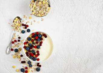 Granola with yogurt and berries for a healthy breakfast. Yogurt bowl with granola, cranberries and blueberries, top view, copy space.
