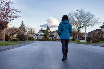 Woman walking on a street in a residential neighborhood of modern city suburbs. Fraser Heights, Surrey, Vancouver, BC, Canada.