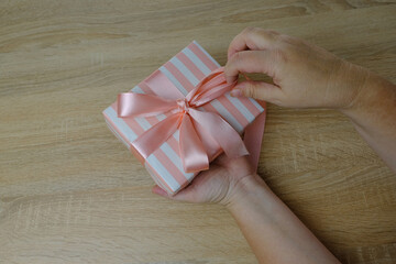 closeup female hands holding box with gift, bouquet of white, pink roses, box with gift with satin...