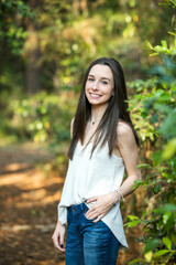 Fototapeta premium A beautiful happy teenage brunette girl outdoors in a wooded area in the spring