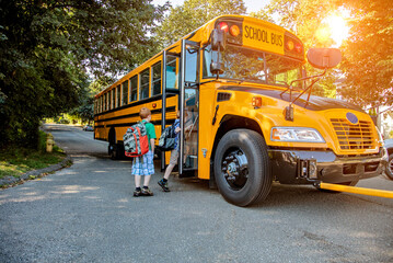 A young boy getting onto a school bus in sunshine - 502968468
