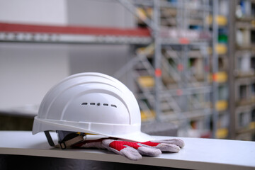 white hardhat, work gloves, helmet on background of buildings, protection inspecting at...