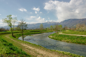 Fototapeta na wymiar Italian rural landscape. Meschio River with hills in the background. Cordignano, Treviso, Italy.