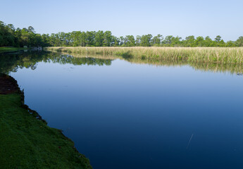 Calm river water reflections under blue sky