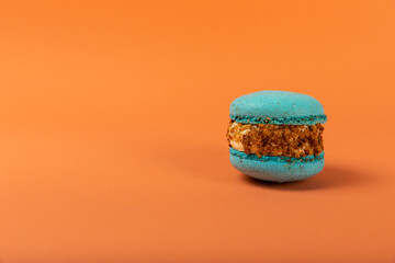 French macaroons on an orange background. Macarons with dor blue and pear. French dessert. Sweet...