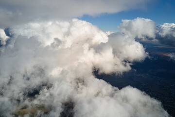 Aerial view from airplane window at high altitude of earth covered with white puffy cumulus clouds