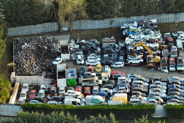 Aerial view of big parking lot of junkyard with rows of discarded broken cars. Recycling of old...