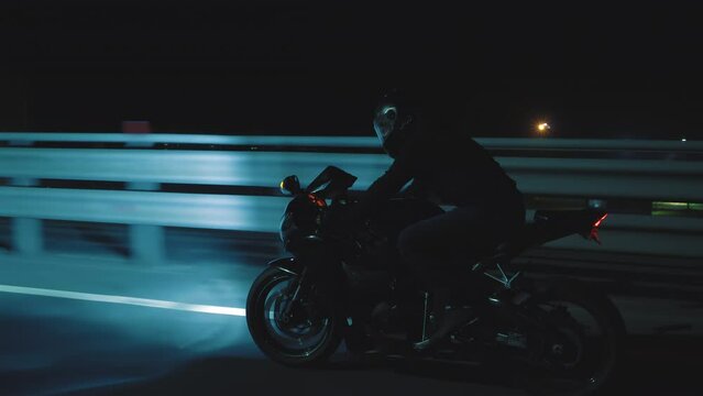 A man rides a sports motorcycle through the city at night