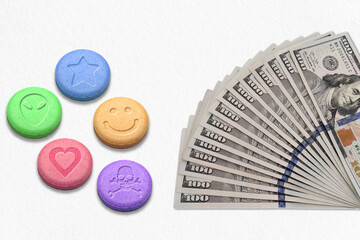 Ecstasy pills with One hundred dollars bills on a white background
