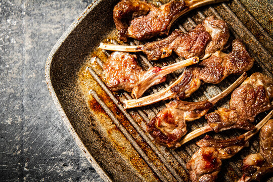 Fragrant grilled lamb rack on a stone board. On a black background. High quality photo