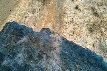 Aerial view of grassland field burning with red fire during dry season. Natural disaster and climate change concept