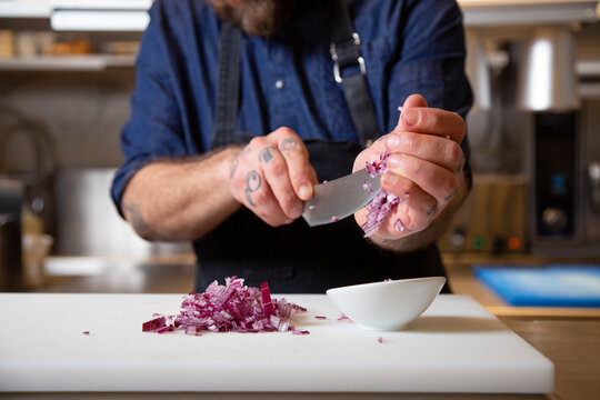 Anonymous chef cutting onion in kitchen