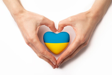 High angle view of child hands holding ukraine flag painted heart isolated on white background