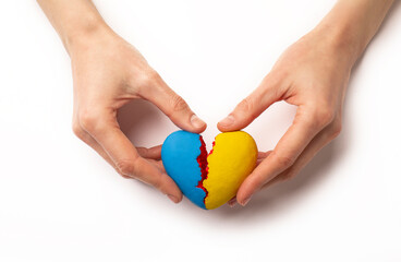 Hands holding a broken heart of Ukraine, war on a white background