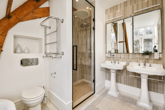 Interior of stylish bathroom with shower cabin and white ceramic sinks