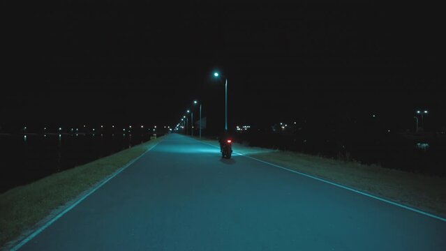 A man moving away on a sports motorcycle into the distance against the backdrop of a night city
