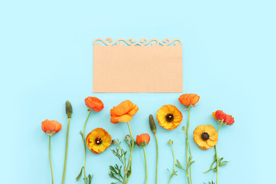 Top view image of yellow flowers composition and empty note over blue pastel background