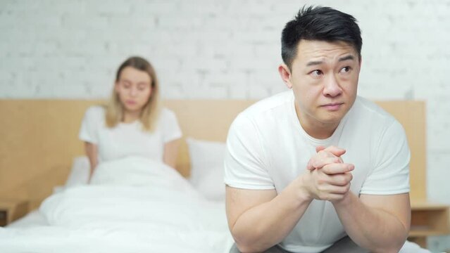 Young unhappy family couple problem in bed. Upset young asian man sitting at home after quarrel. husband and wife are difficult in a relationship. Divorce, marriage, conflict, crisis, love concept