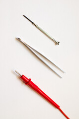 Tweezers and screwdriver for repairing electronic gadgets on a white background. The desktop of a mechanical engineer