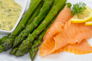 close up of delicious salmon with asparagus and sauce on white plate