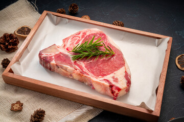 Raw T-bone steak beef with rosemary on wooden plate, T-bone steak beef (Sliced) on black wooden...