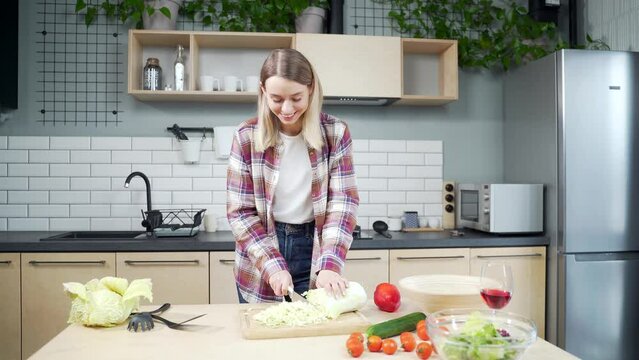 young woman chef coach tells a recipe how to cook healthy food. Looking at the camera. The female records video or online lessons or course. standing in the kitchen at home. Blogger. Webcam view
