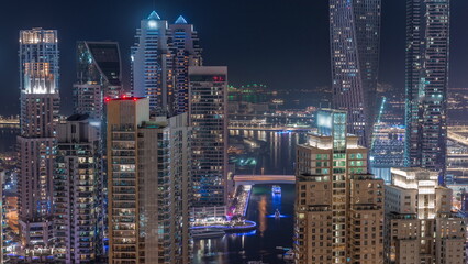 Promenade and canal in Dubai Marina with luxury skyscrapers around night timelapse, United Arab Emirates