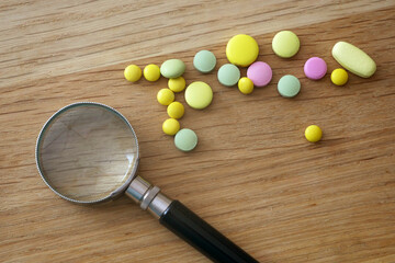 magnifying glass, pills and tablets on blue background. checking ingredients and effectiveness of medicine