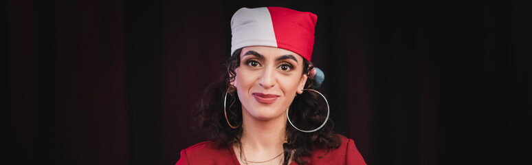 Positive gypsy soothsayer looking at camera isolated on black, banner.