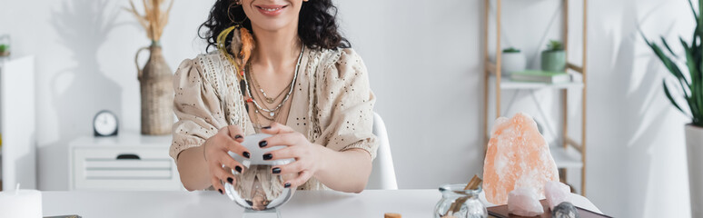 Cropped view of smiling medium touching magic orb at home, banner.