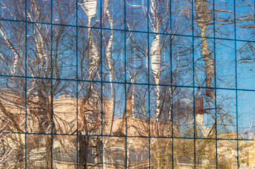 abstract background with reflection of trees and sky in the glass wall of the building