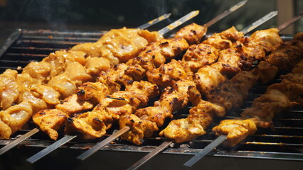 Shashlik - traditional Georgian barbecue. Closeup of raw roasted marinated meat barbecue shish kebab shashlik on steel metal skewers lying grill fire brazier with charcoal.  Making barbecue
