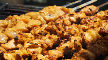 Shashlik - traditional Georgian barbecue. Closeup of raw roasted marinated meat barbecue shish kebab shashlik on steel metal skewers lying grill fire brazier with charcoal.  Making barbecue