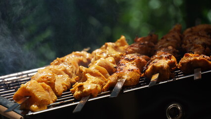 Shashlik - traditional Georgian barbecue. Closeup of raw roasted marinated meat barbecue shish kebab shashlik on steel metal skewers lying grill fire brazier with charcoal.  Making barbecue