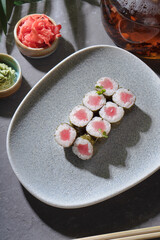 Sushi and rolls on a gray dish with Chinese chopsticks, wasabi and sauce.