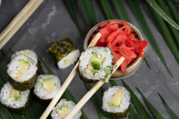Sushi and rolls on a gray dish with Chinese chopsticks, wasabi and sauce.