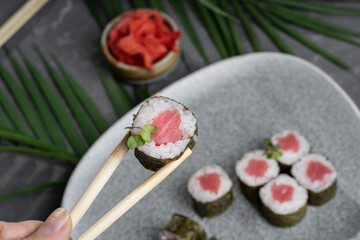 Sushi and rolls on a gray dish with Chinese chopsticks, wasabi and sauce.